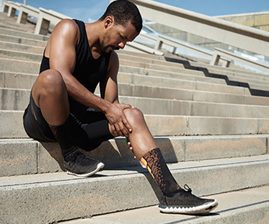 Athletic man holding his knee in pain, symbolizing sports-related knee injury treatment at Champion Chiropractic in Coral Springs