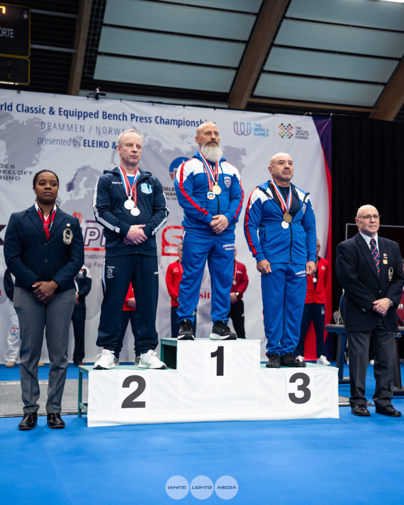 Dr. Damian Fronzaglia stands atop the podium after winning gold at the 2025 IPF World Bench Press Championships in Drammen, Norway
